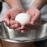 closeup of a man holding a mozzarella in his hands